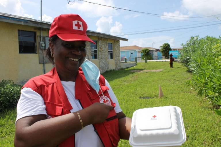 Annie Beckles, a Red Cross volunteer, holds a boxed meal in her hand.