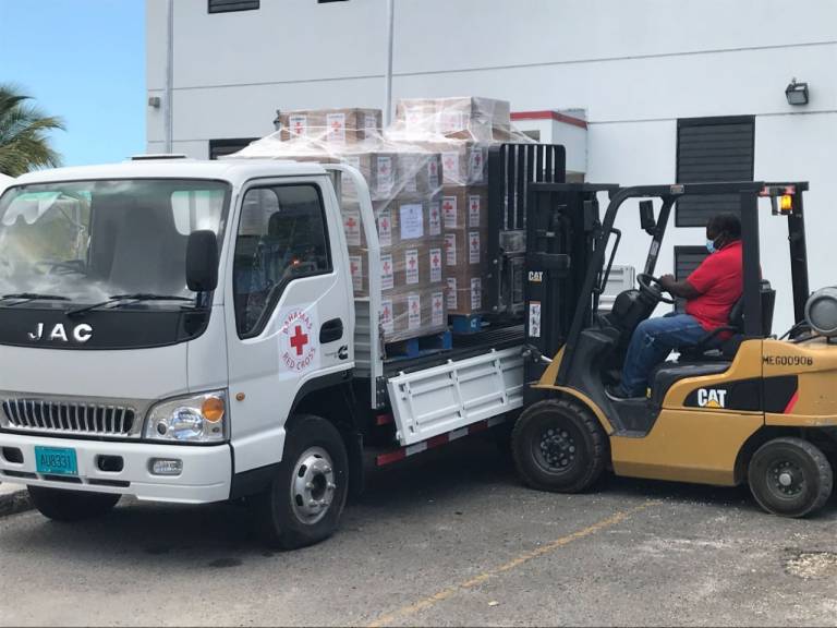 A Red Cross volunteer moving food parcels off of a flatbed truck.