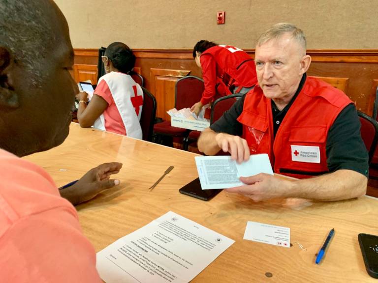 A Red Cross volunteer explains how to use funds for Hurricane Dorian recovery to an evacuee on Nassau.