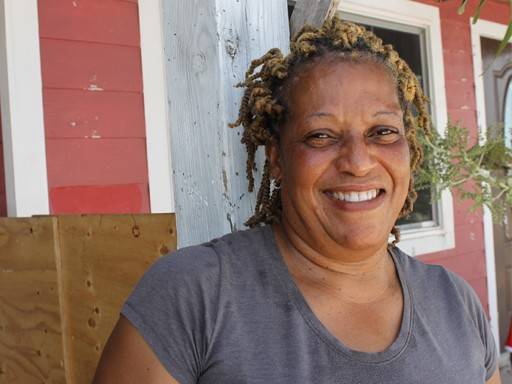 Erlis Mcintosh smiles as she watches as workers make progress repairing her roof ahead of another hurricane season.