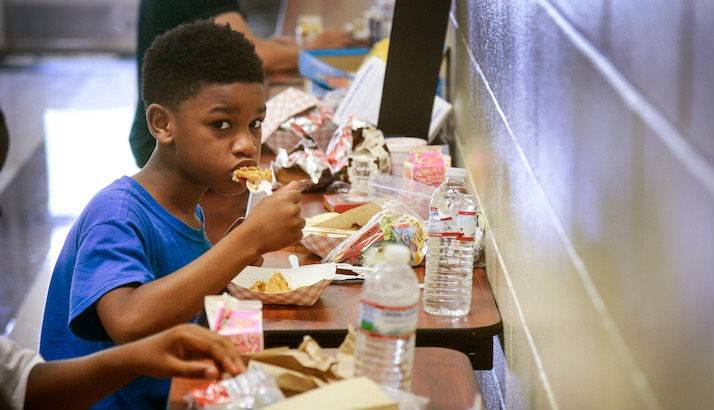 Deshawa, a 7-year-old resident of the evacuation shelter located at Evans High School, digs into his lunch.