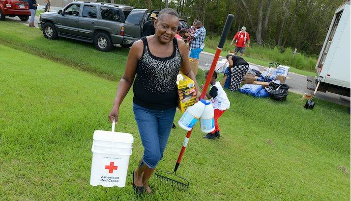 A woman receiving disaster relief supplies from the Red Cross truck.