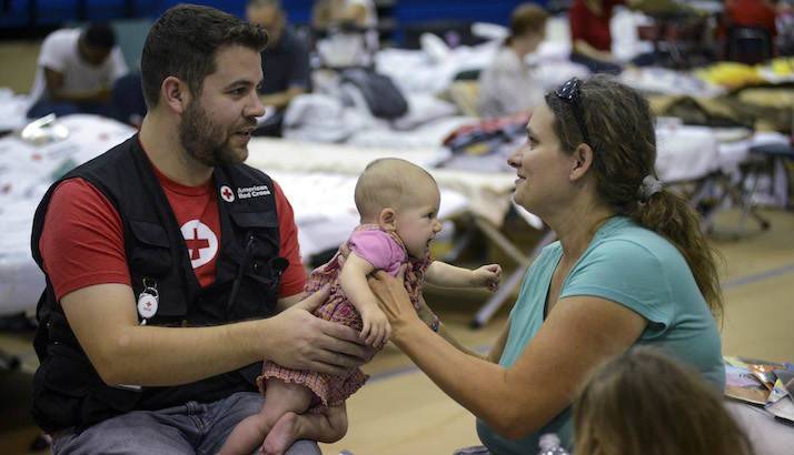 A Red Cross volunteer passing a baby back to its mother at a shelter in Panama City, Florida.