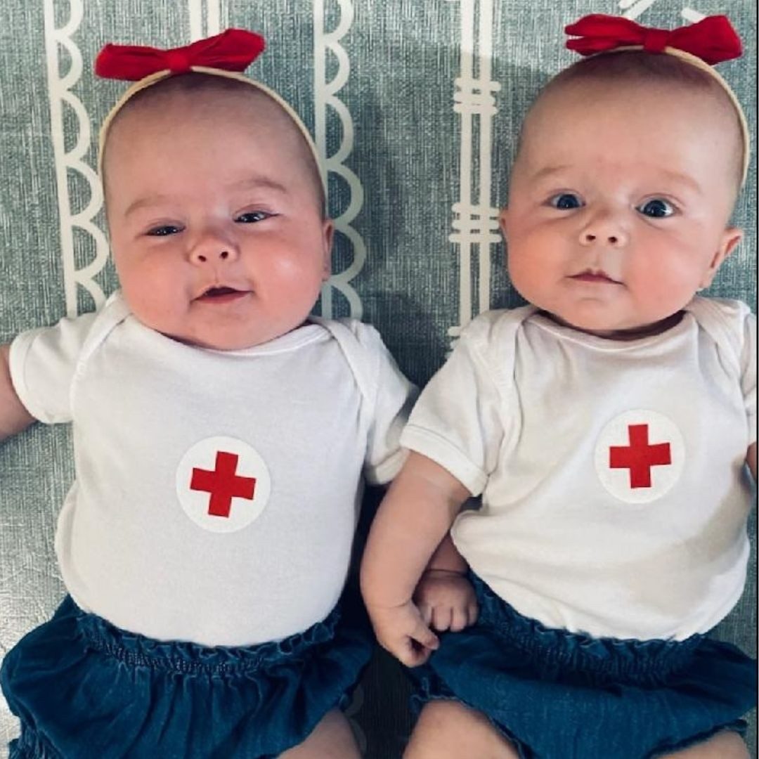 baby twin sisters with red cross outfits