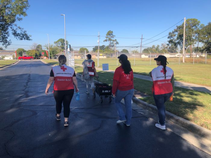 red cross volunteers walking down the street with wagon