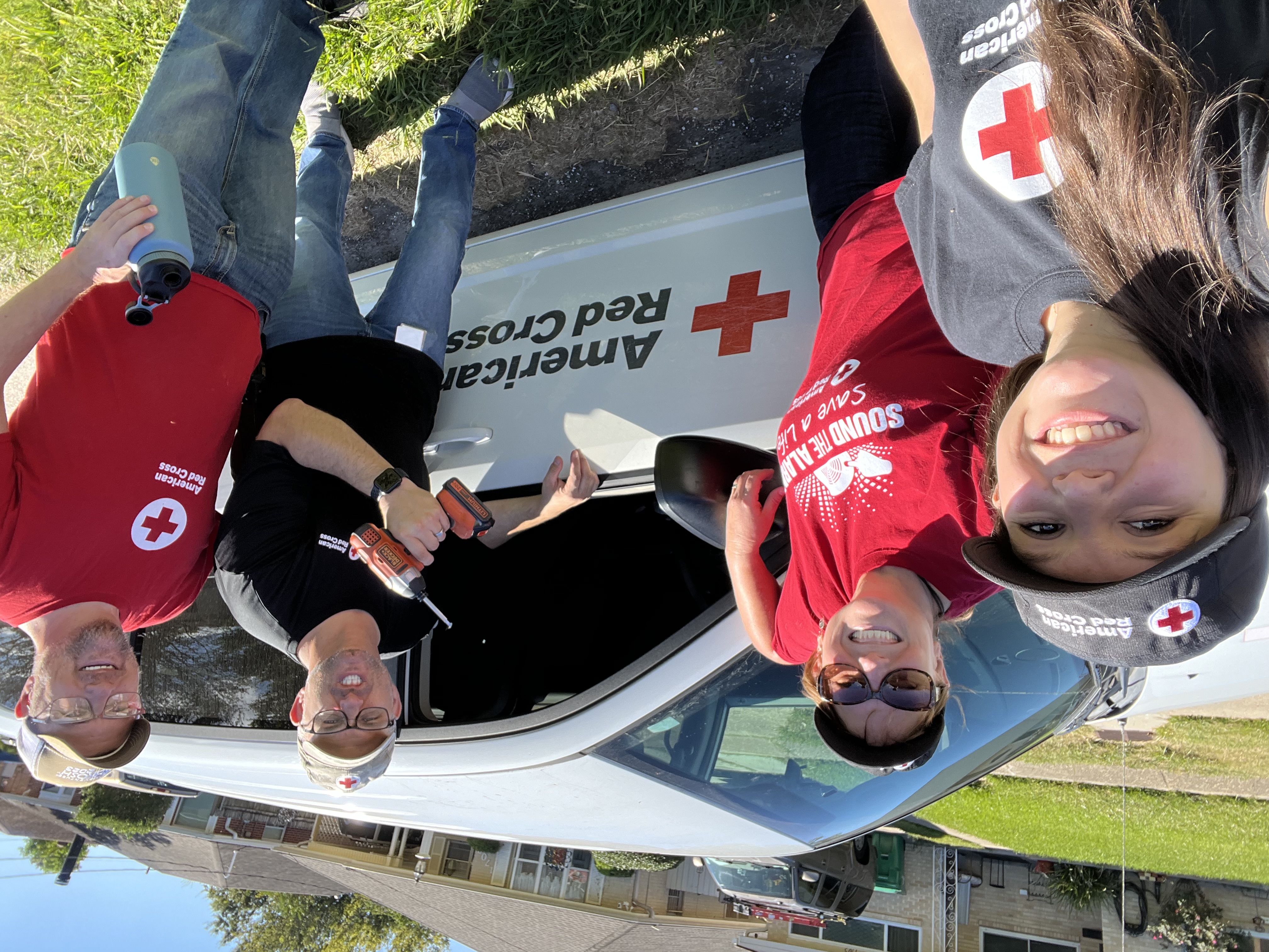 red cross volunteers smiling in front of a red cross vehicle