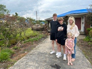 Amy Dougherty and her 3 kids standing in front of their home.