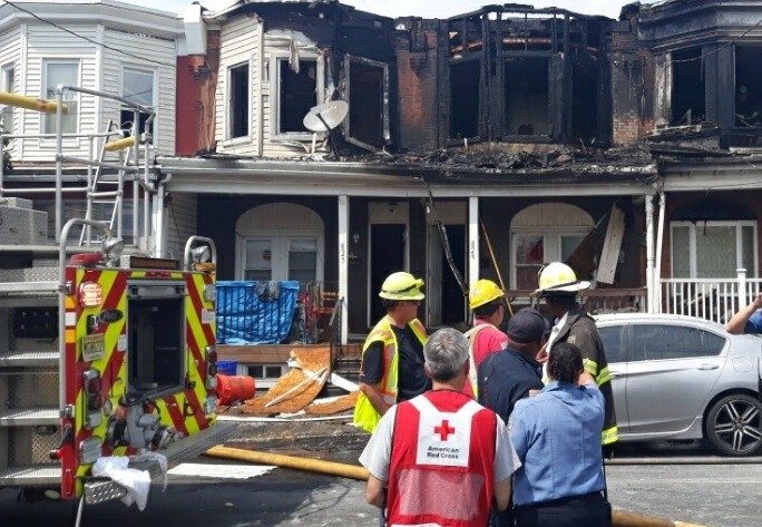 red cross volunteers and firefighters surverying a fire damaged home
